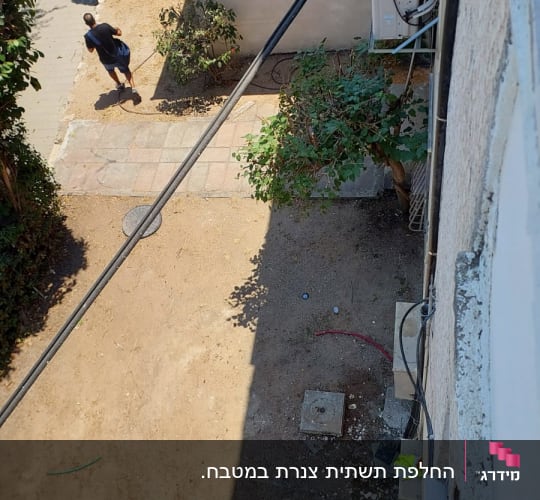 אדם הולך ליד קיר עם צינורות ומזגן חיצוני